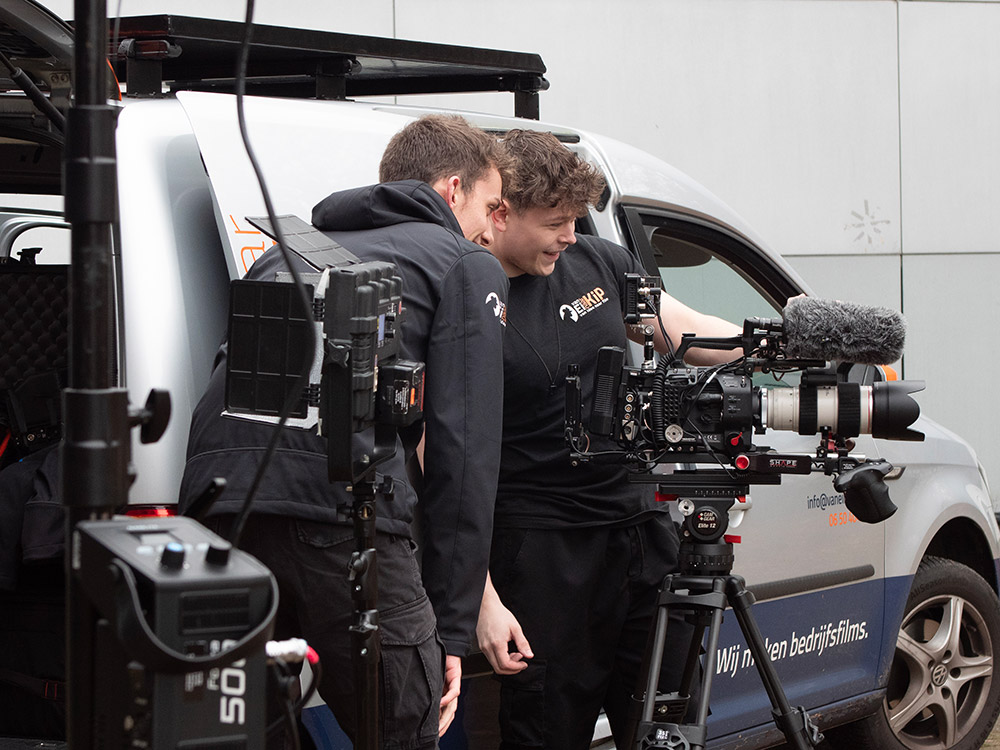 Cameraman en assistent bekijken samen de opgenomen beelden terug tijdens filmopnames voor een bedrijfsfilm.